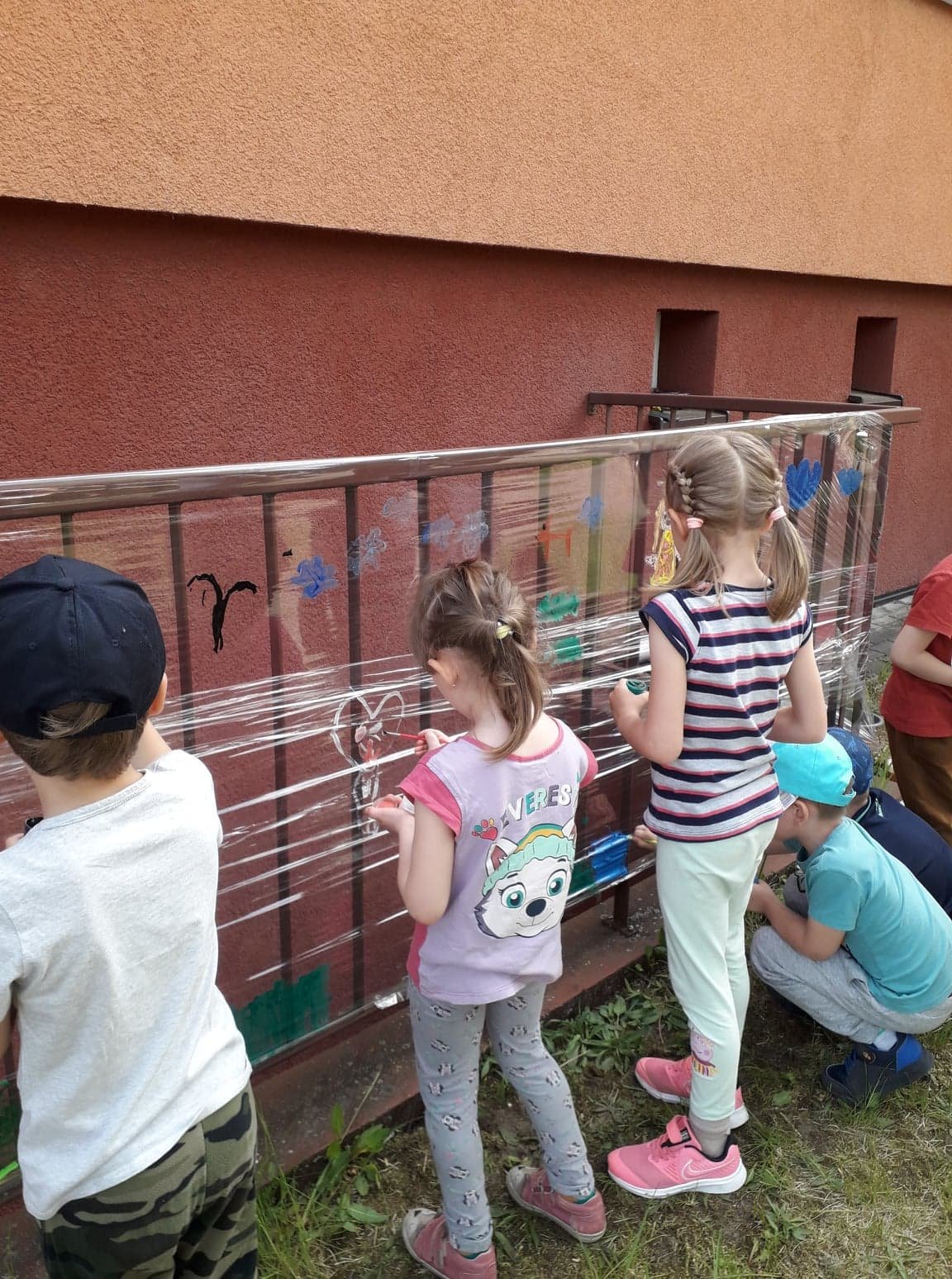 przedszkolaki maluj� farbami po celofanie na imprezie inegracyjnej na boisku szkolnym